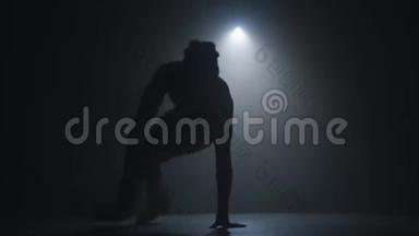 一位才华横溢的年轻舞者在聚光灯前的舞台上跳嘻哈<strong>街舞</strong>的剪影